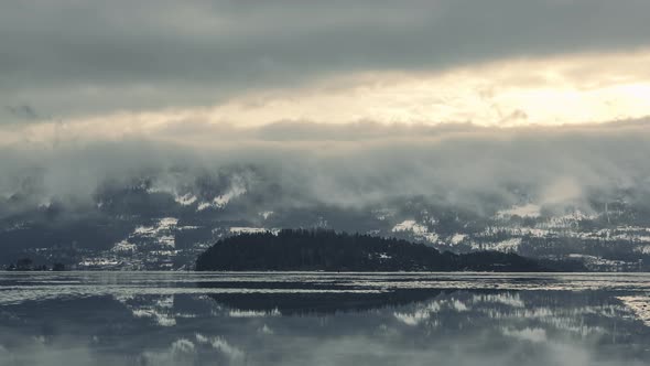 Waterfall of clouds over Haugastol, Norway lakeside in winter -time lapse