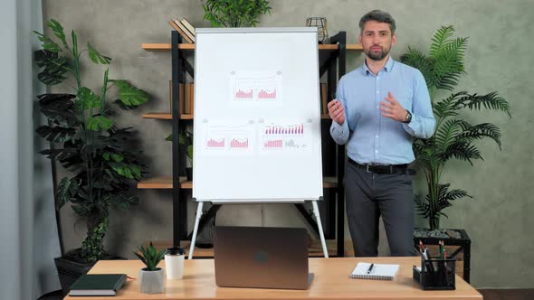 Man teacher stands near flip chart tells teaches students remote web video call