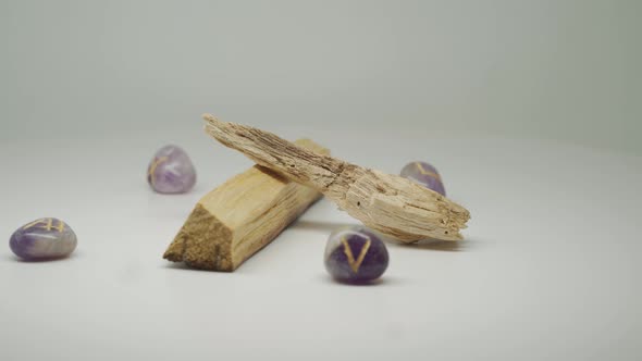 Two Pieces Of Palo Santo Wood Surrounded By Purple Gem Stones Moving In A Circular Motion - Close Up