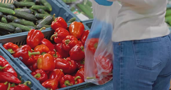 Closeup a Woman's Hand in Medical Gloves Takes Vegetables From a Supermarket Shelf