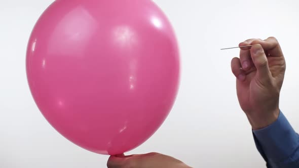 Man Pierces a Balloon with a Needle