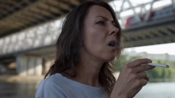 Portrait of a Discontented Woman Smoking Under a Railway Bridge