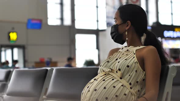 Asian Pregnant Woman in a Medical Mask Sitting on the Chair in the Airport
