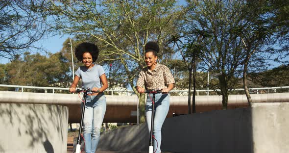 Two mixed race women riding electric scooter