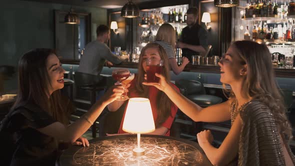 Three Happy Women Sitting at the Small Table in Bar