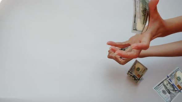 Woman's Hands Catch Two 100 US Dollar Banknotes Falling in Slow Motion Against White Background.