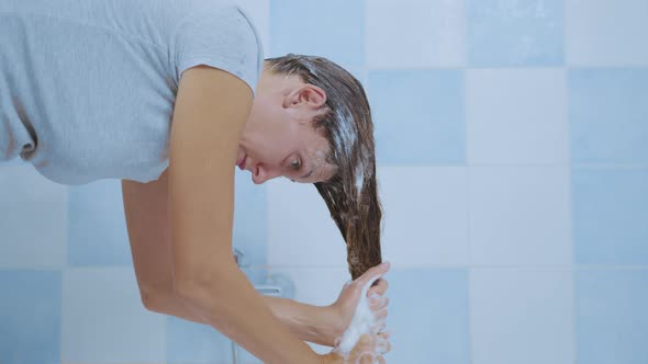 Young Woman Washes Away the Shampoo From Her Hair While. Concept of Cleanliness of Hair and Body.