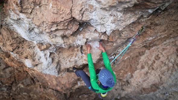 Slow Motion From Above of Woman Rock Climber Climbs on Overhanging Cliff By Hard Route