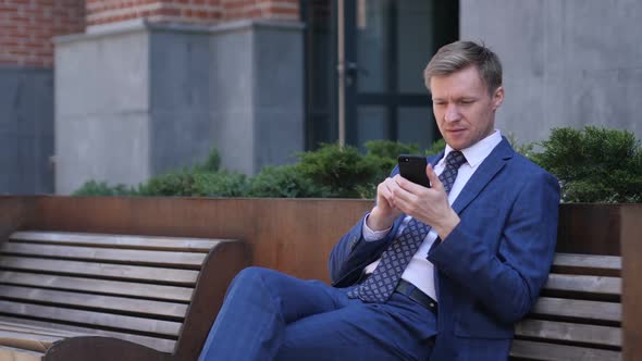 Excited Businessman Celebrating Success While Using Smartphone