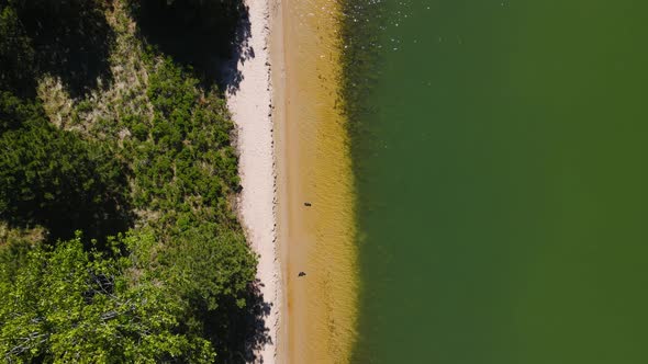 Bird's eye track of the light shoreline at a man-made lake.