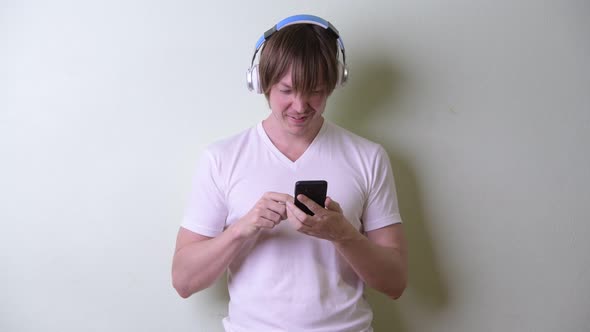 Happy Young Man with Long Hair Using Phone and Listening To Music