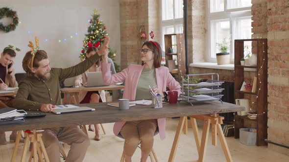 Colleagues High-Fiving in Office on Christmas Eve