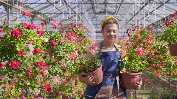 Woman Florist Walking Among Flowers in Greenhouse