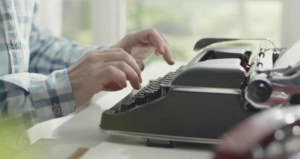 Man sitting at desk and typing on a typewriter