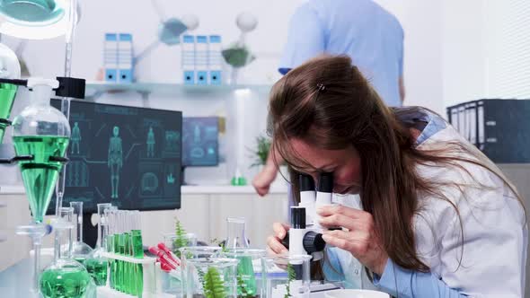 Revealing Shot of Female Scientist Looking Into the Microscope