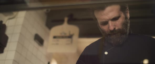 A bearded hispanic chef working in the restaurant kitchen. Slow motion, medium shot.