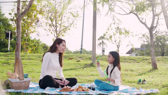 Happy family picnic. A little girl blowing soap bubbles with parents with fun and enjoyed together