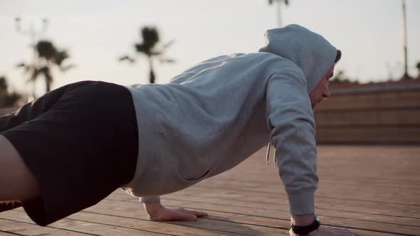 Enduring Man Is Doing Pushups in Park Area in City in Daytime