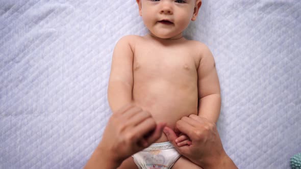 Mom Raises the Hands of the Lying Baby Alternately