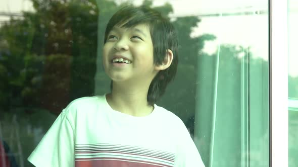 Asian Child Smiling And Watching Out The Window