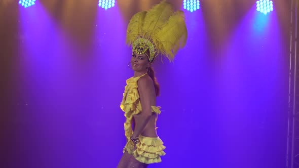 Gorgeous Young Woman Is Dancing in a Yellow Carnival Costume and a Plush Feather Headdress. The