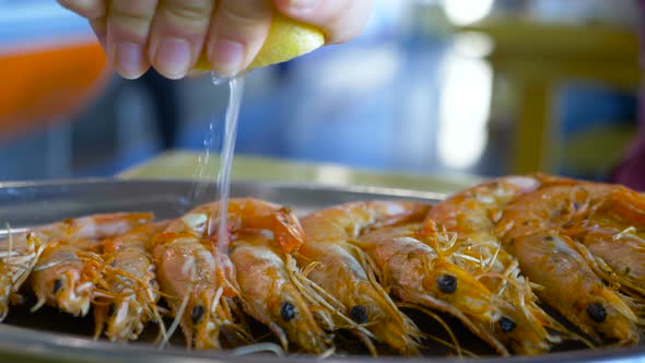 Red Shrimps on Plate and Hand Squeezing Fresh Lemon Juice