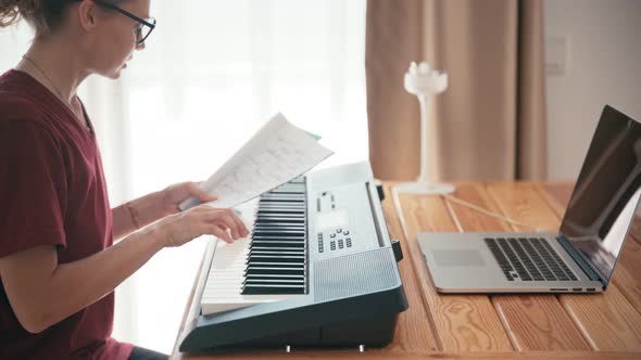 Young Woman Learning Piano with an Online Course Using Her Laptop