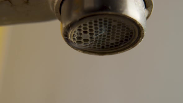 Macro shots of a dripping water faucet wasting water