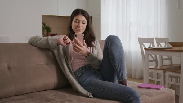 Young Woman Surfing on the Internet Using Her Smart Phone in Her Living Room with Various Facial