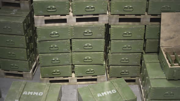 Huge stack of ammo boxes with RPG missiles and rifle ammunition in warehouse.