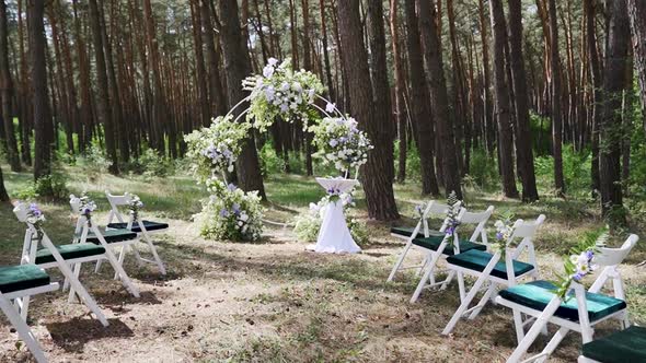 Beautiful arch decoration wedding ceremony in pine forest. Chairs, floristic