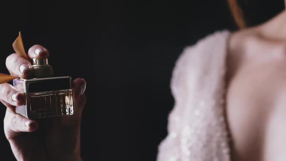 Lady in Shiny Dress Sprays Fragrance on Black Background