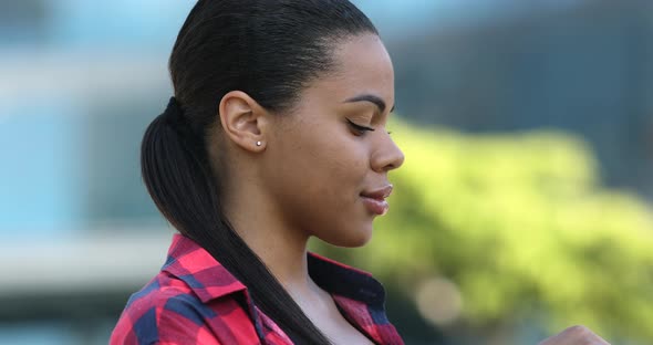 Young african american woman putting in wireless earphones.