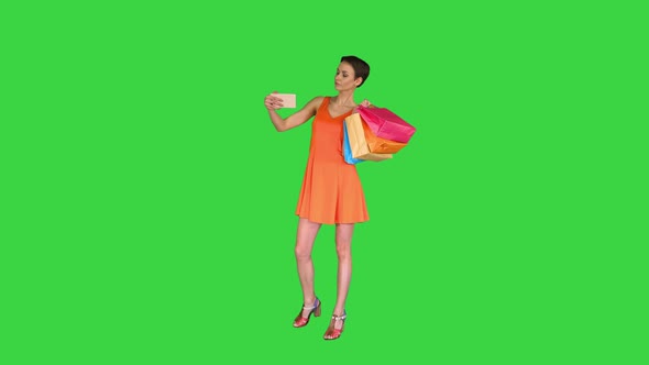 Attractive Young Woman Holding Different Blank Shopping Bags Making Selfie on a Green Screen, Chroma