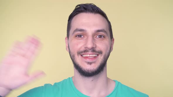 Cheerful Young Man Waving Hand and Smiling at Camera