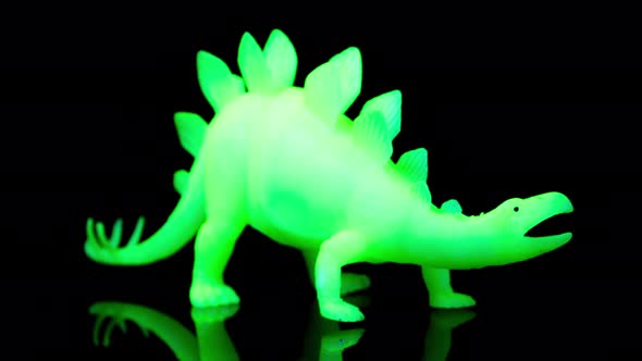 Green Toy Dinosaur Turning Agaisnt Black