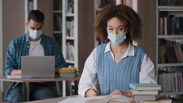 Students Study in Library Young Woman in Protective Mask Writing Notes Does Homework Showing Gesture