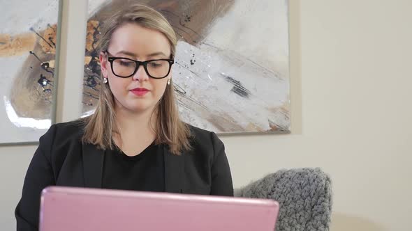 A Young Female Business Entrepreneur Looking Down And Typing On Her Laptop