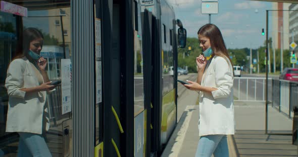 Young Woman in Medical Face Mask Gets on the Yellow Tram at the Public Stop. Covid-19, Health and