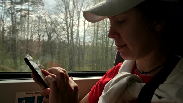 Woman in Train Looking Into Phone Shooting Video View From the Window