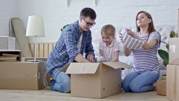 Young Family Unpacking Clothes in New House