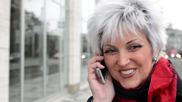 Middle Aged Woman Phones with Smartphone - Urban Street with Cars in the City - Closeup