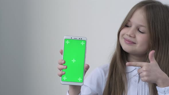 Schoolgirl in White School Blouse Shows Phone with Green Screen Mock Up Cellphone Mobile Telephone