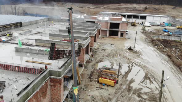 Aerial View of A Small Construction Crane Lifts a Heavy Metal Structure. Flying Around the alt