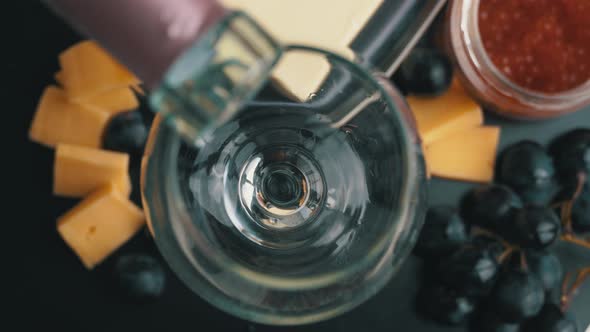 Rose Wine is Poured Into a Glass With Snacks