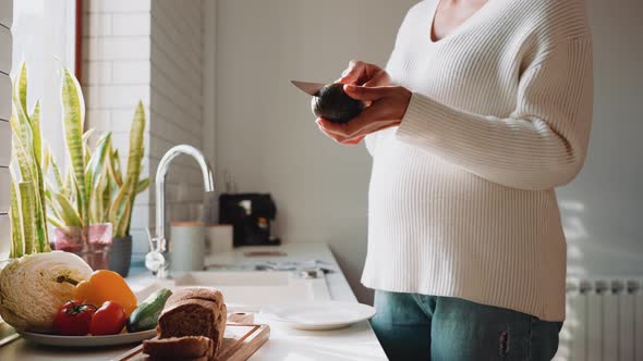 African pregnant woman cuts avocado