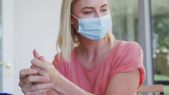 Mother and daughter wearing face masks sanitizing their hands at home