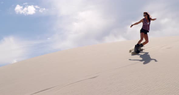 Woman sand boarding on the slope in desert 