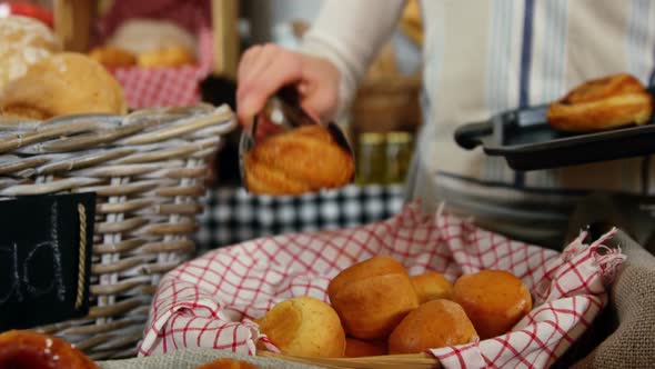 Female staff arranging baked croissant in basket at bakery section