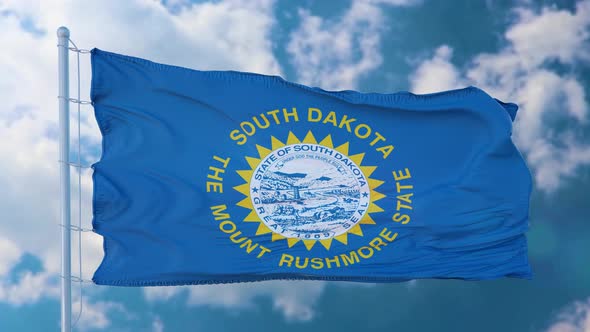 South Dakota Flag on a Flagpole Waving in the Wind Blue Sky Background